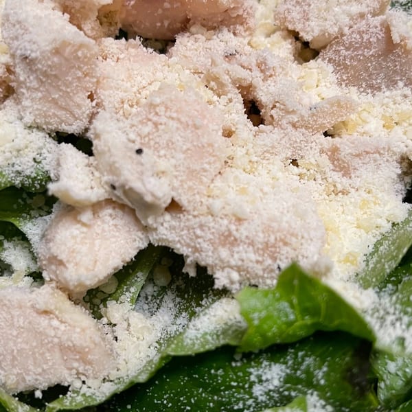 Close-up of a Caesar salad with chicken and generous grated Parmesan cheese at Bobo's Pizza.